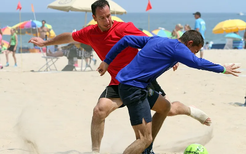 Spillere i aksjon på sandbanen under en strandfotballturnering
